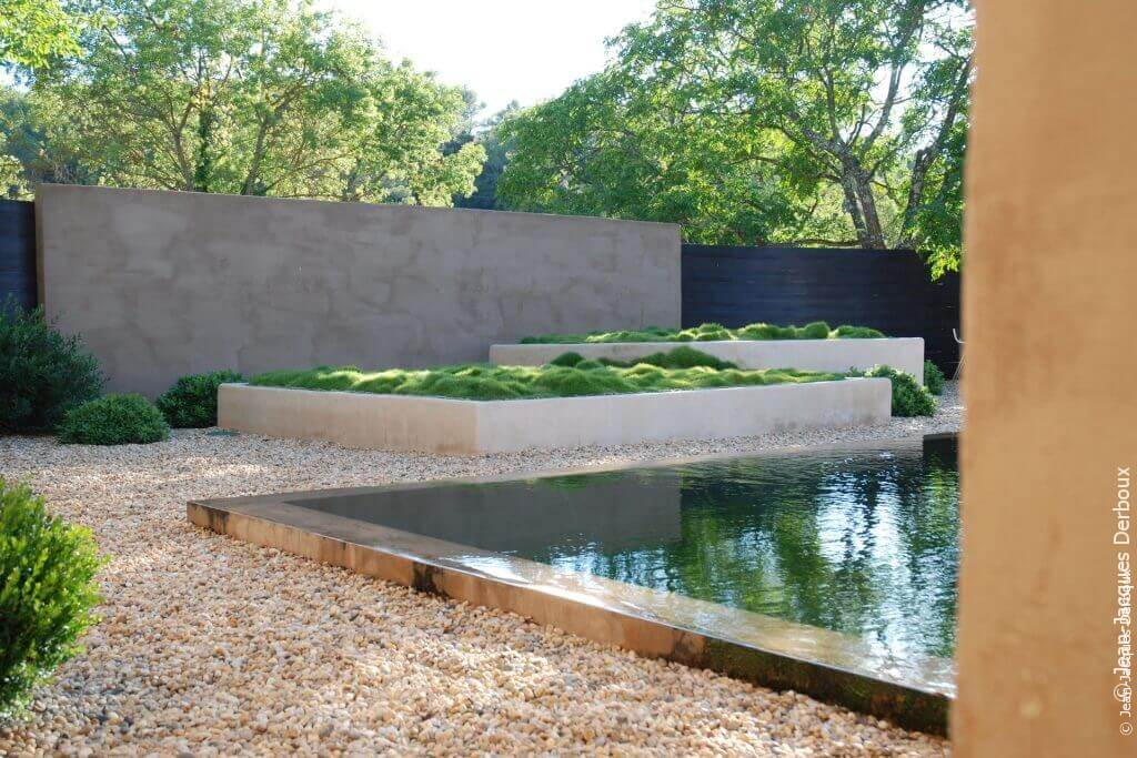 Se rafraichir  Piscine biologique à débordement, eau effet miroir, grande jardinière maçonnée plantée de zoysia, gravier.