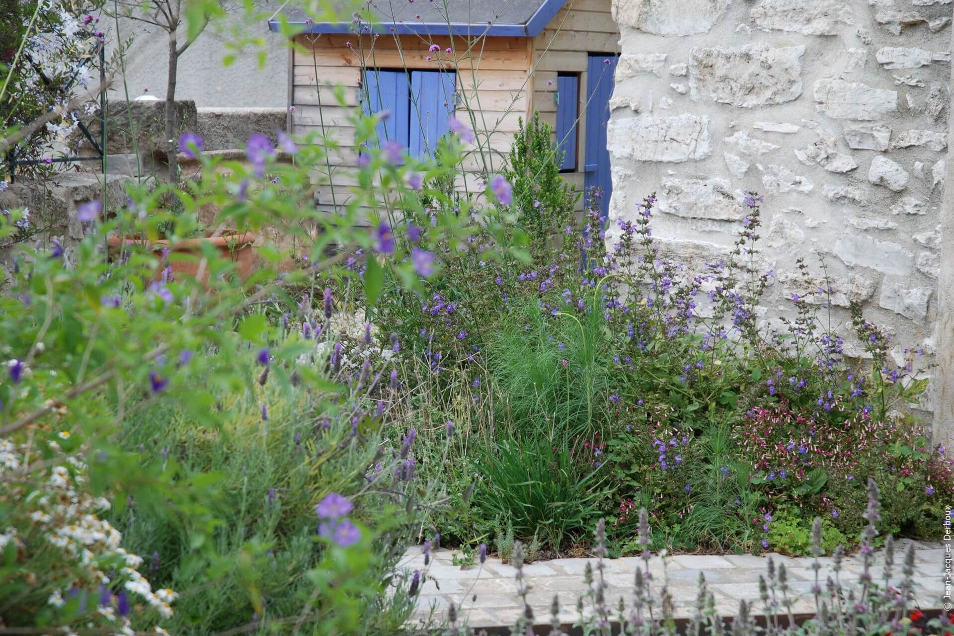 Cabane au jardin, volets bleus, fleurs mauve, esprit champêtre.