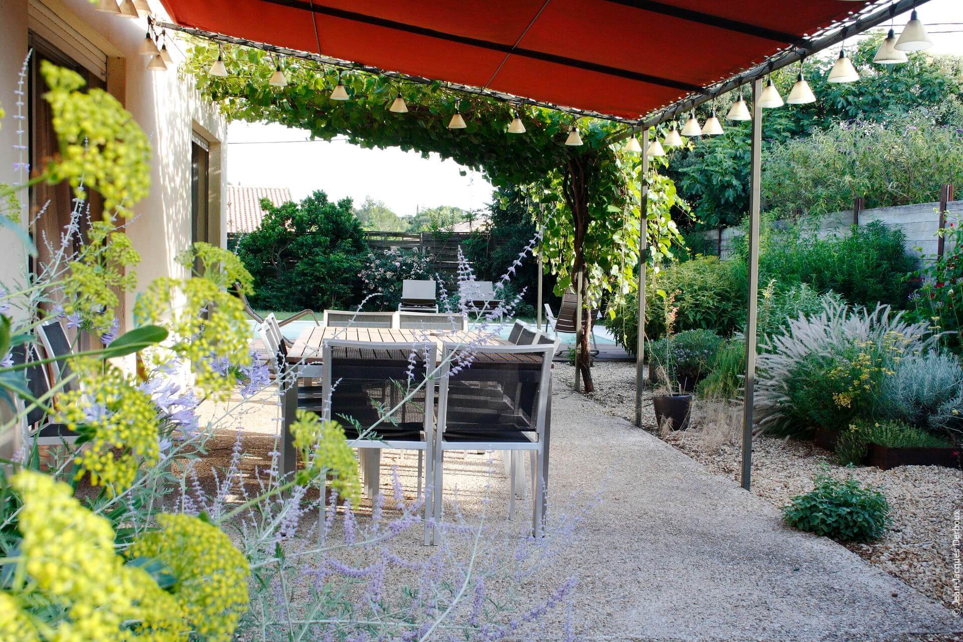 Terrasse pour prendre les repas, mobilier contemporain, treille, ombrage toile imperméable, luminaire de jardin lampion, ombrage vigne, jardin sec.